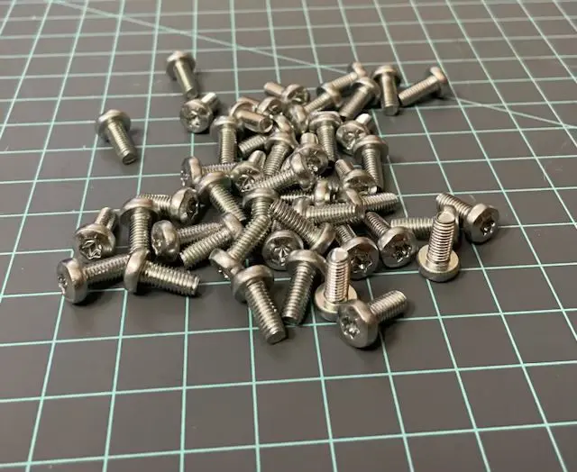 A pile of stainless steel nuts on top of a table.